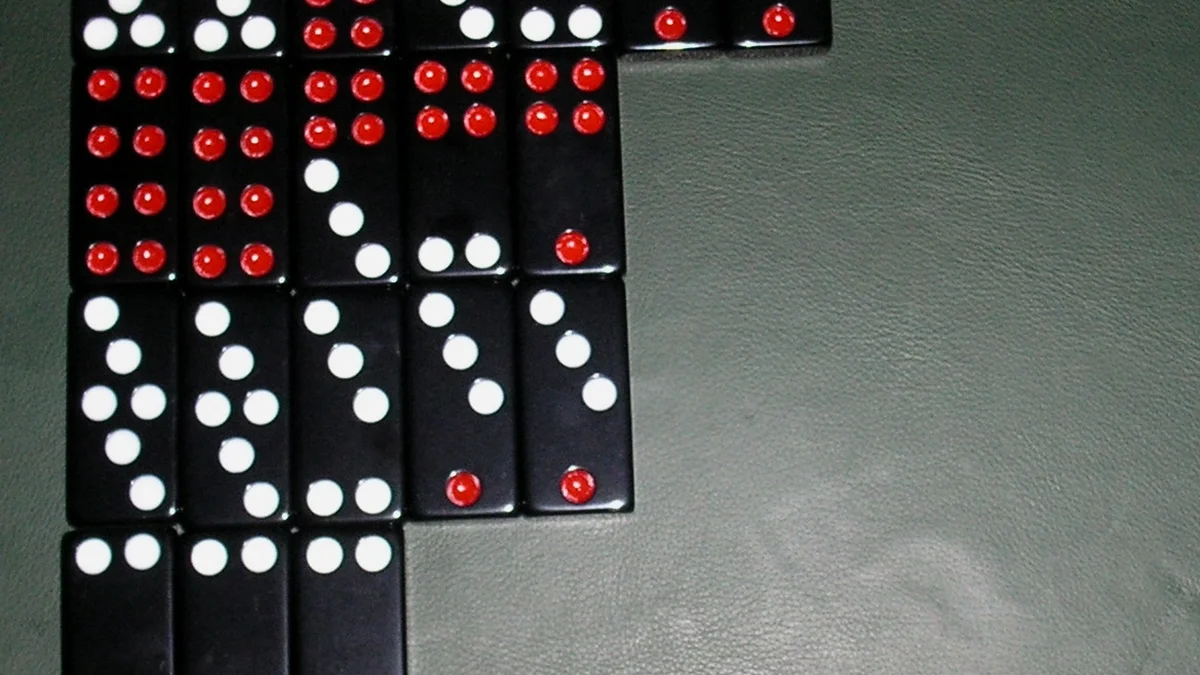 Traditional Pai Gow domino tiles arranged in hierarchical ranking pairs on wooden table